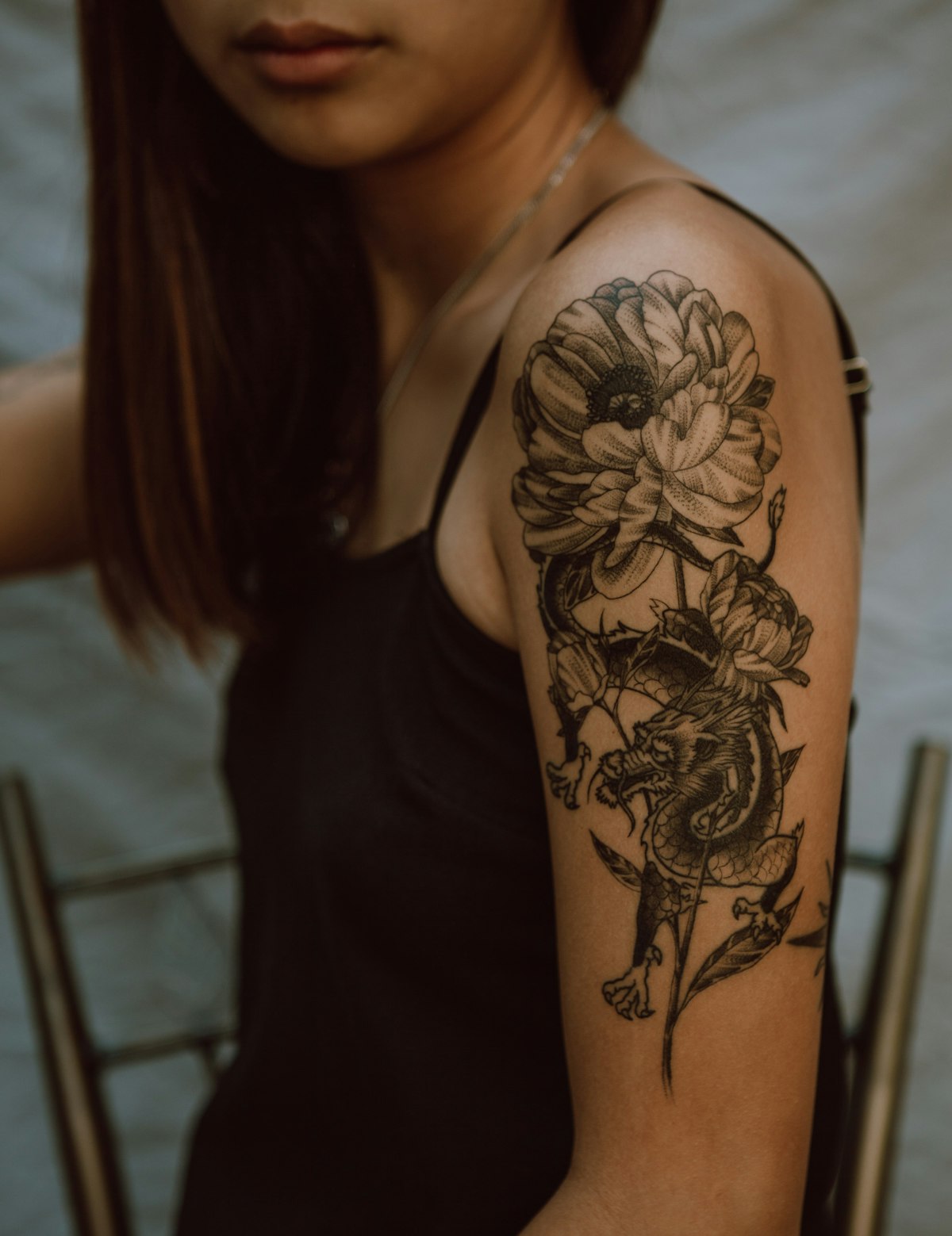 Black-and-Grey-Tattoo mit Drache und Pfingstrosen auf dem Oberarm